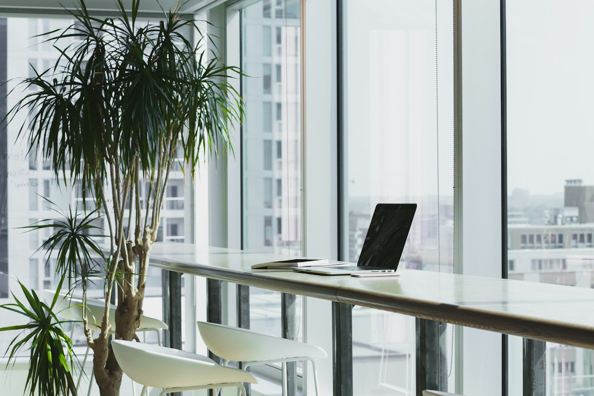 A bright, modern office interior with a laptop on a table overlooking a city skyline