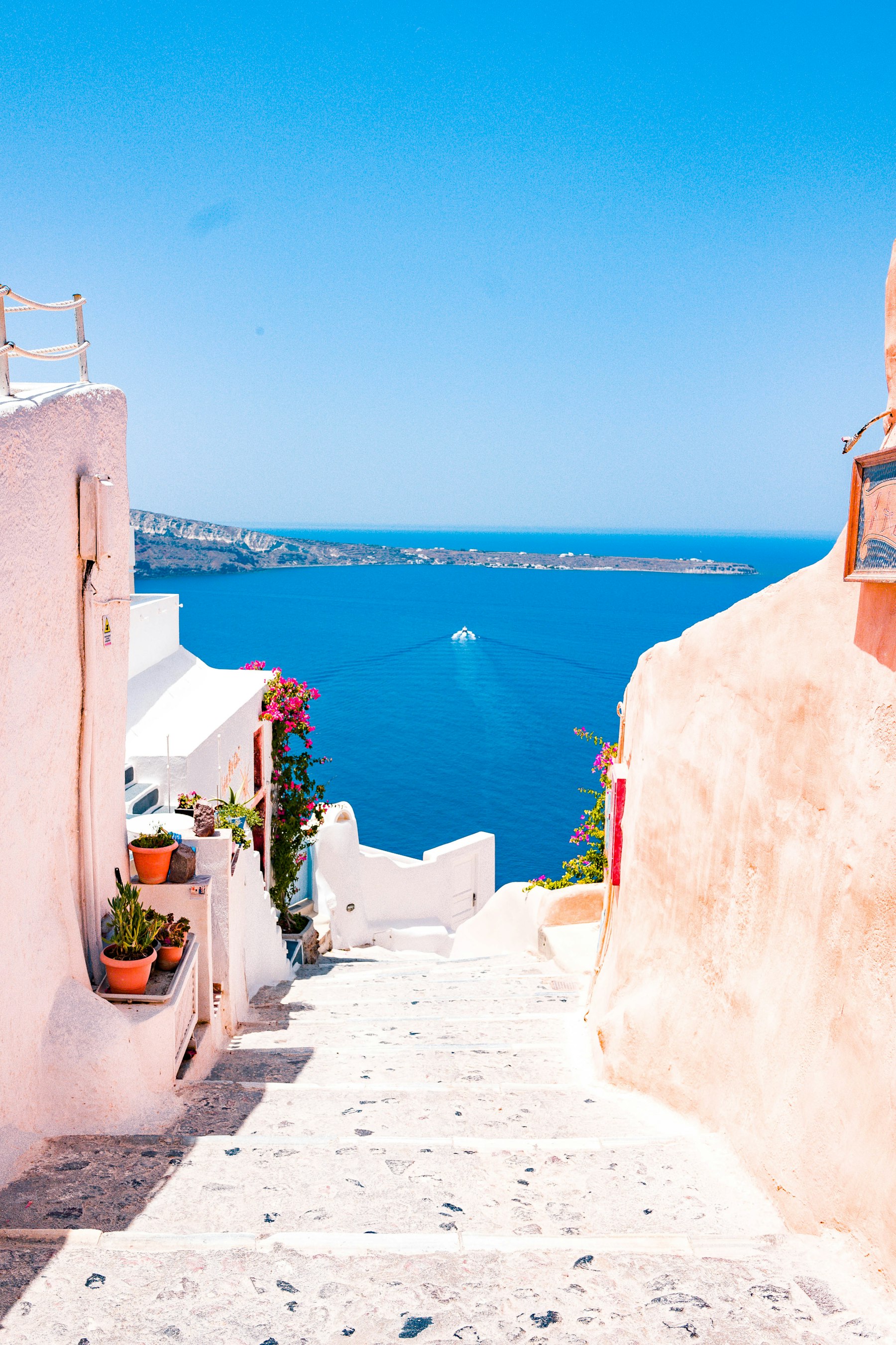 A sunlit stairway between coastal buildings overlooking the sea